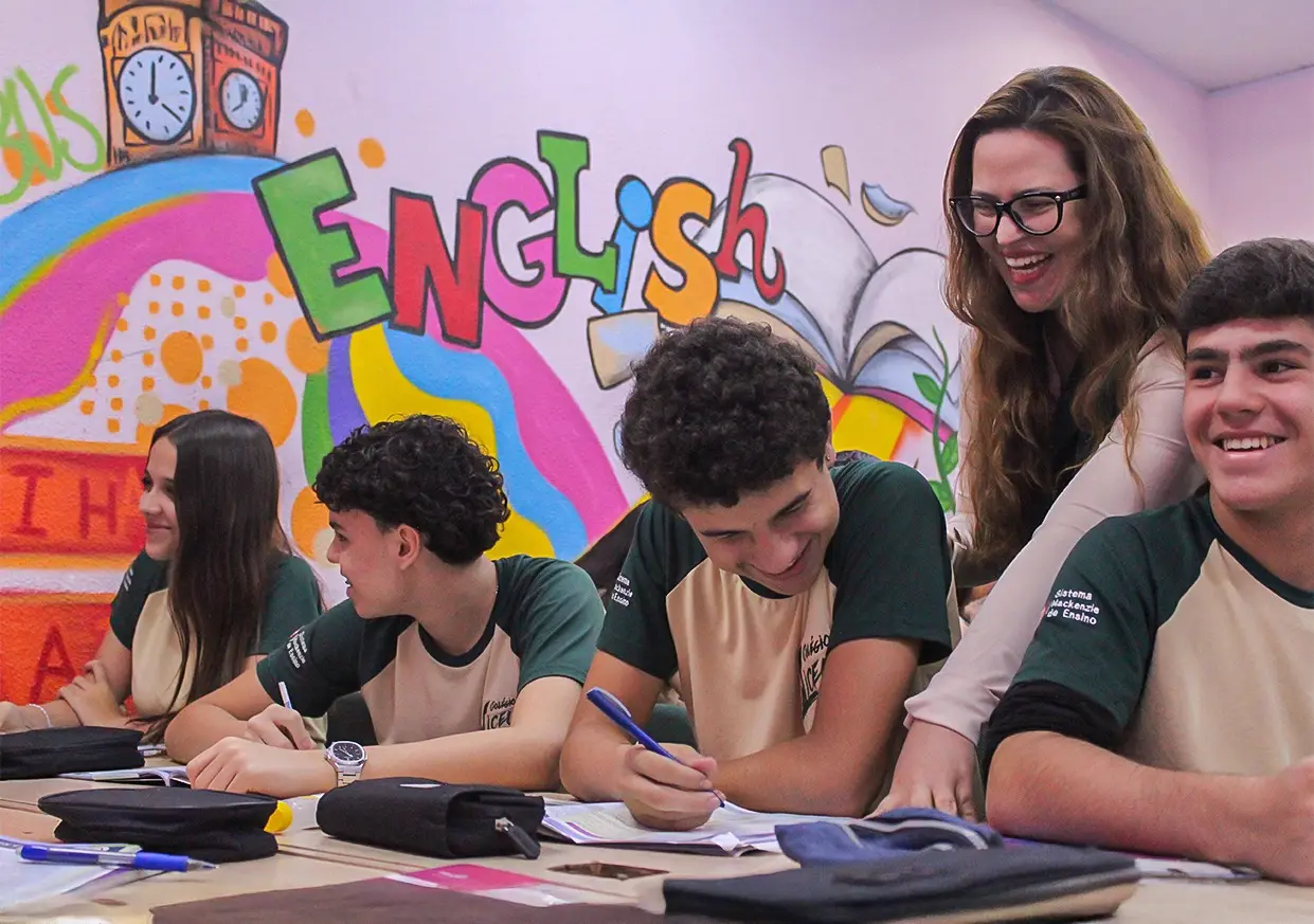 Professora e alunos do Ensino Médio durante uma aula de inglês, na sala com mural English